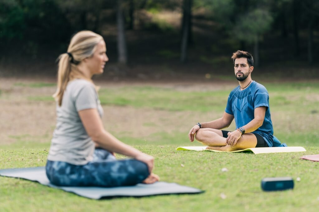 Man doing yoga with a female instructor in a forest